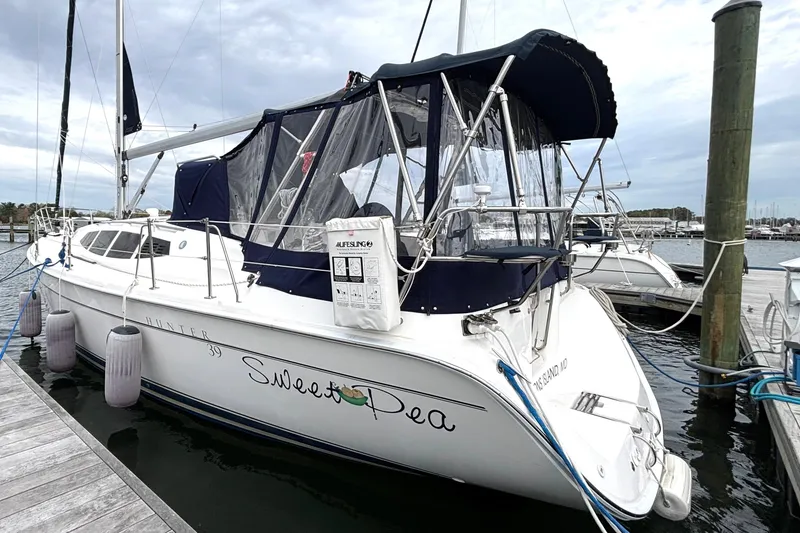 Slide: The Image of 2011 Hunter 39 sailboat docked, featuring a navy canopy and "Sweet Pea" name on the stern. - 33