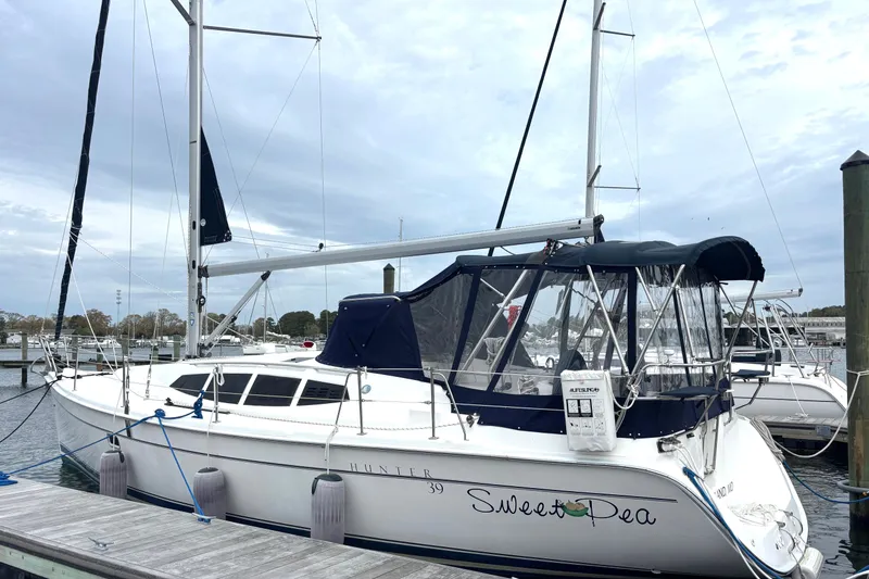 Slide: The Image of 2011 Hunter 39 sailboat docked, featuring a sleek design and blue canopy. - 35