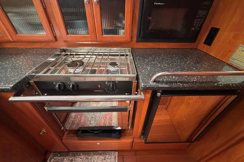 Slide: The Image of 2011 Hunter 39 yacht kitchen with stove, oven, and microwave in wooden cabinetry. - 5