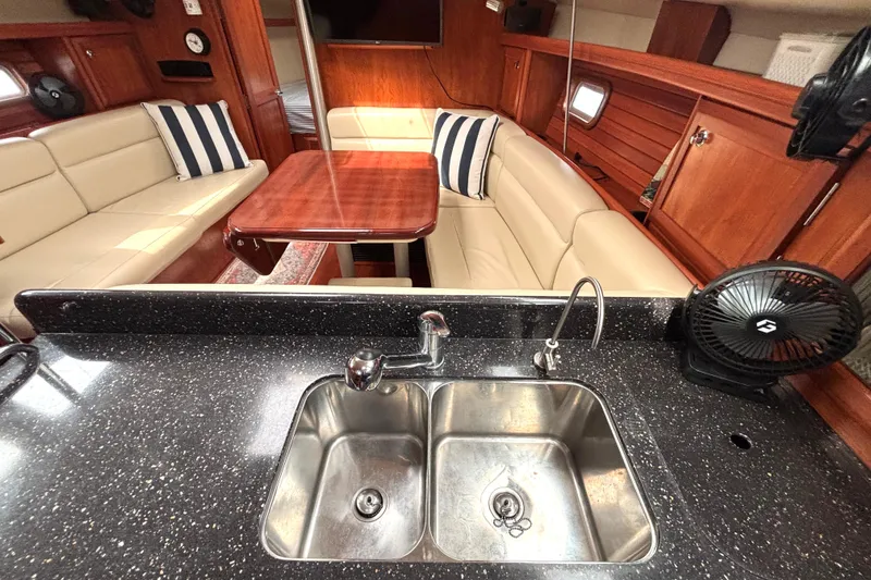Slide: The Image of Luxurious 2011 Hunter 39 yacht interior with elegant seating, wooden table, and modern kitchen sink. - 9