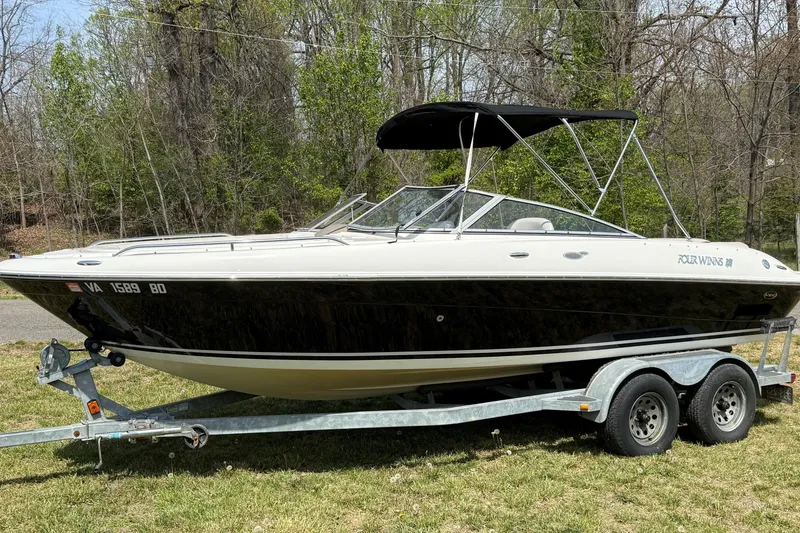 The Image of 2003 Four Winns 210 Horizon boat on trailer, parked on grass with trees in background. - 0
