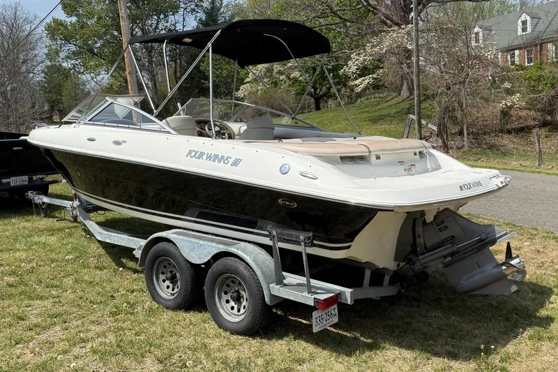 Slide: The Image of 2003 Four Winns 210 Horizon boat on trailer, parked on grass. - 2