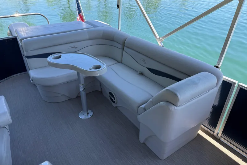 Slide: The Image of 2017 Bennington 21 SLX pontoon boat interior with seating and table on calm water. - 11
