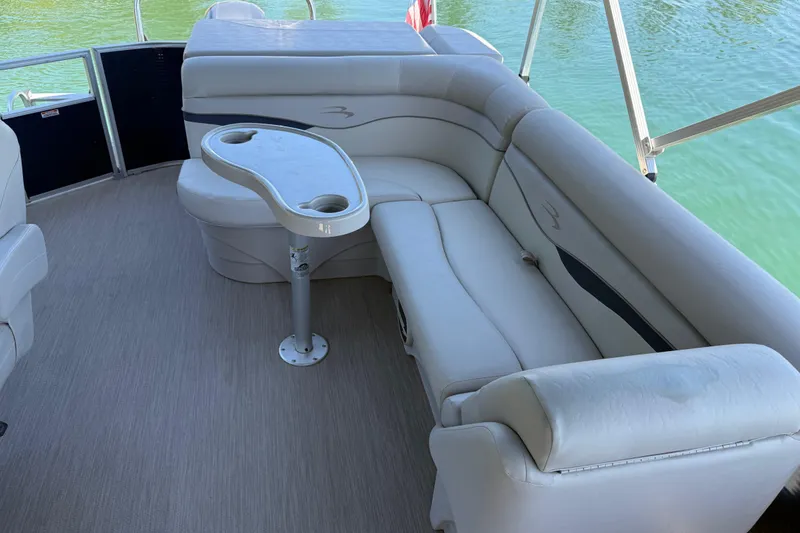 Slide: The Image of 2017 Bennington 21 SLX pontoon boat interior with plush seating and table on calm water. - 12