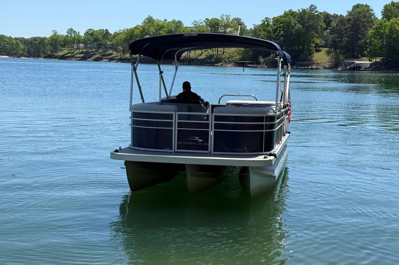 Slide: The Image of 2017 Bennington 21 SLX pontoon boat on a serene lake with lush green surroundings. - 3