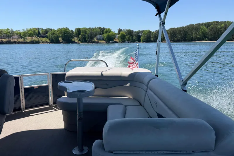 Slide: The Image of 2017 Bennington 21 SLX pontoon boat cruising on a scenic lake with American flag. - 37