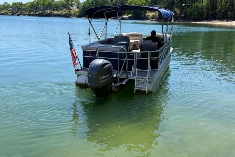 Slide: The Image of 2017 Bennington 21 SLX pontoon boat on a serene lake with American flag. - 5