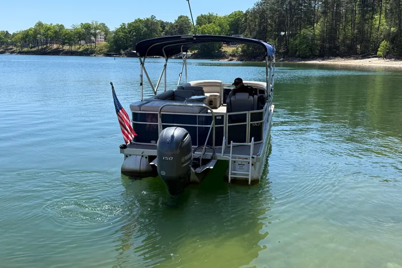 Slide: The Image of 2017 Bennington 21 SLX pontoon boat on a serene lake with American flag. - 6