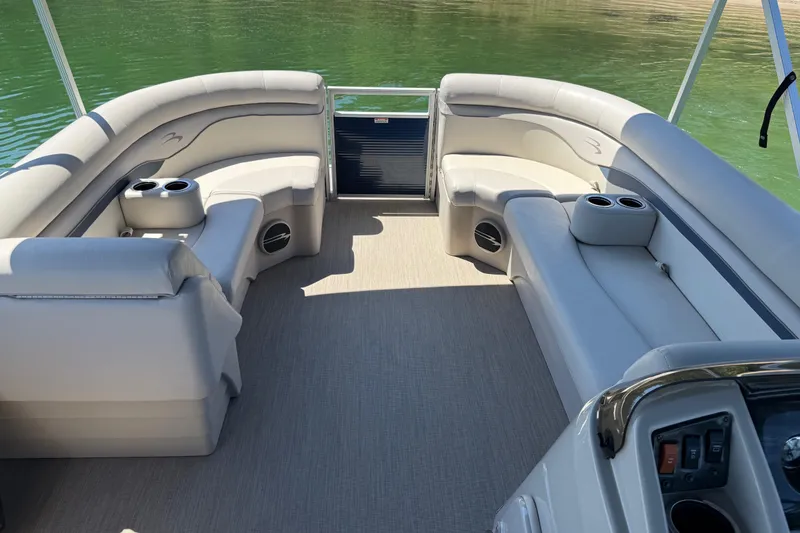 Slide: The Image of 2017 Bennington 21 SLX pontoon boat interior with plush seating and cup holders on a sunny day. - 7