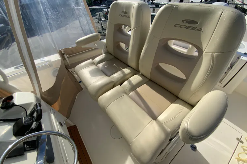 Slide: The Image of 2017 Cobia 277 Center Console boat with beige cushioned seating and steering wheel. - 15