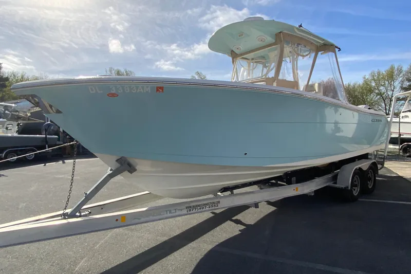 Slide: The Image of 2017 Cobia 277 Center Console boat on trailer, light blue hull, parked outdoors. - 5