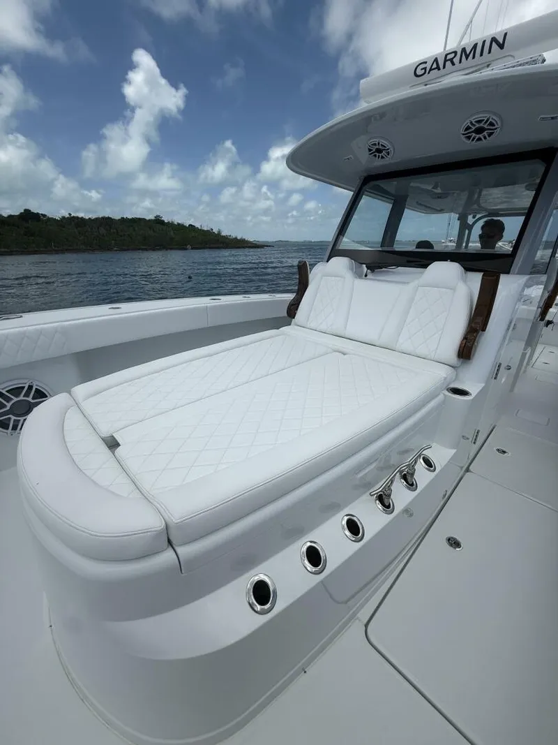 Slide: The Image of Luxurious 2026 Freeman 38 boat with white cushioned seating, under a cloudy sky. - 16
