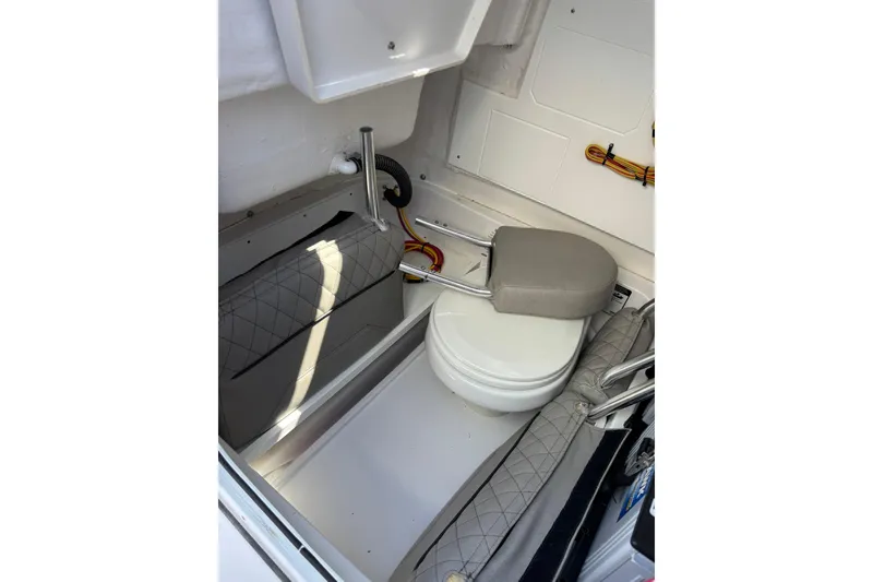 Slide: The Image of 2025 Sportsman Heritage 231 Center Console boat interior with compact marine toilet. - 12