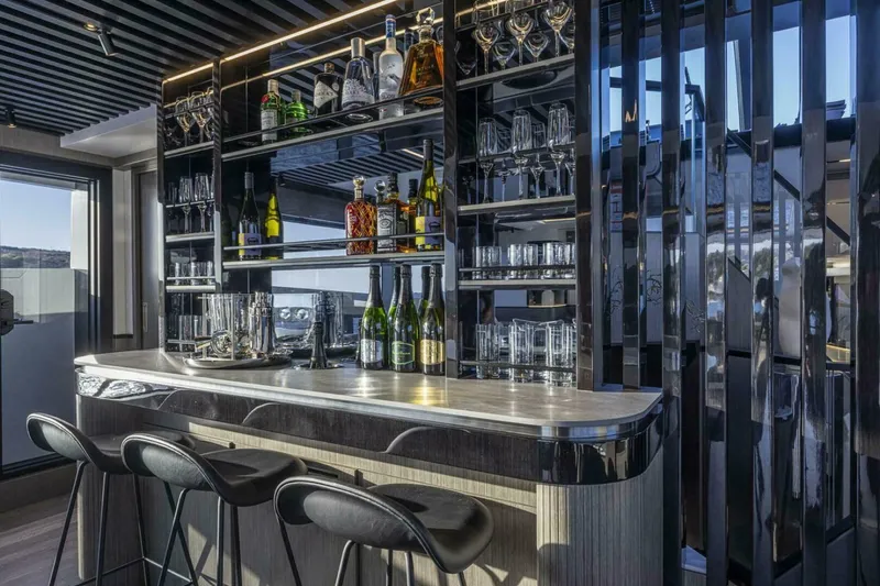 Slide: The Image of Luxurious yacht bar interior with sleek design, featuring stocked shelves and modern bar stools, Pearl 82, 2026. - 17