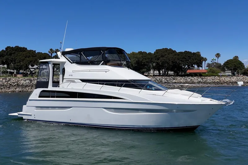 Slide: The Image of 2007 Carver 43 Motor Yacht cruising on a sunny day near a rocky shoreline. - 4