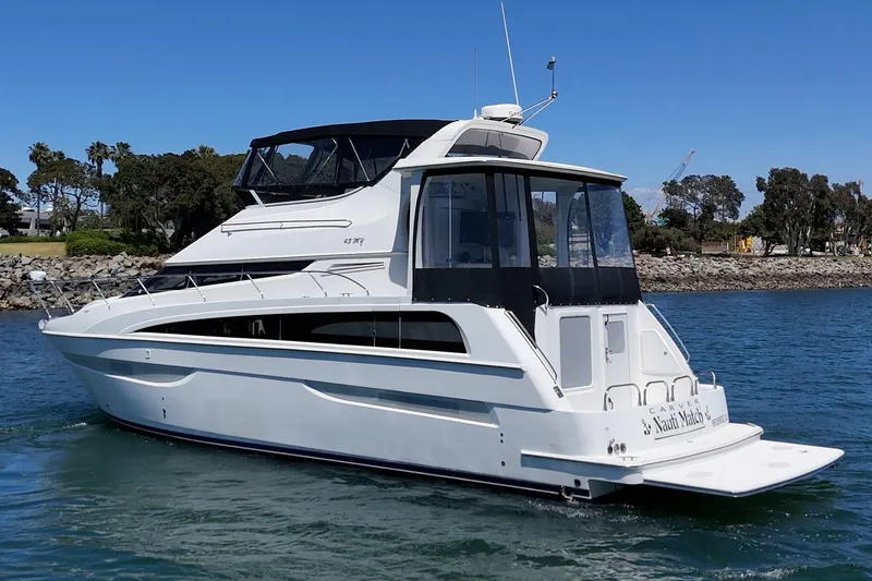 Slide: The Image of 2007 Carver 43 Motor Yacht cruising on a sunny day near a rocky shoreline. - 5