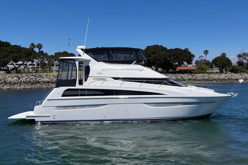 Slide: The Image of 2007 Carver 43 Motor Yacht cruising on a sunny day near a rocky shoreline. - 8