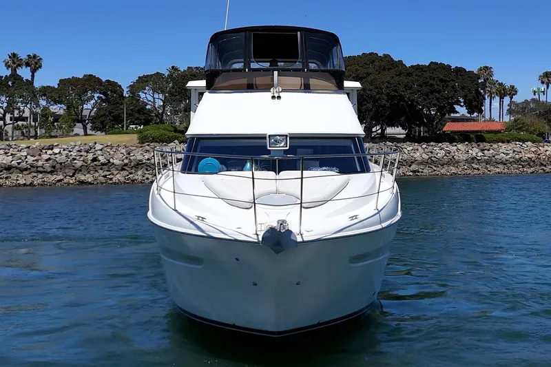 Slide: The Image of 2007 Carver 43 Motor Yacht on water, front view, clear sky, rocky shoreline. - 9