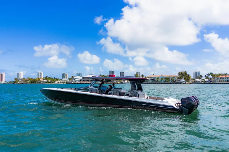 Slide: The Image of 2023 Nor-Tech 500 Sport Center Console boat cruising on a sunny day near a city skyline. - 2