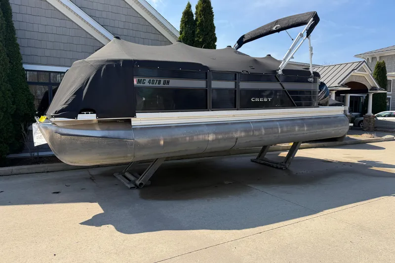 Slide: The Image of 2019 Crest II SLC LTD pontoon boat with cover, parked on a driveway. - 19
