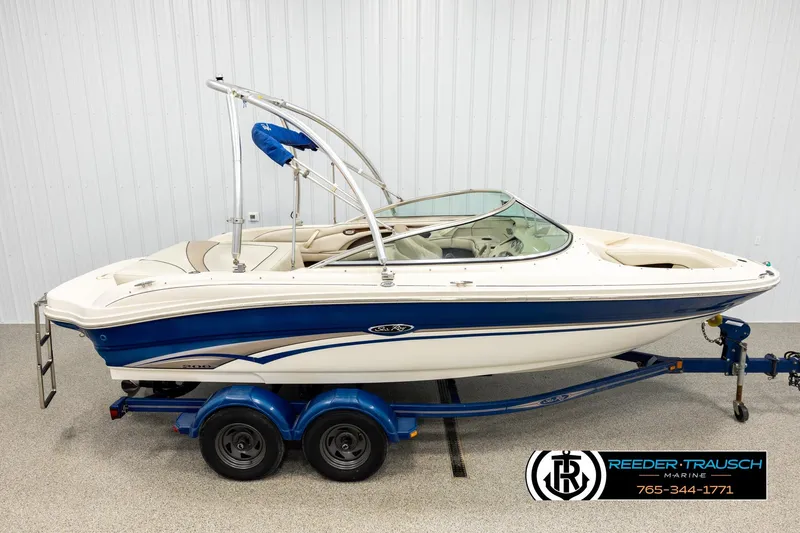The Image of 2003 Sea Ray 200 Bow Rider boat on trailer, blue and white design. - 1