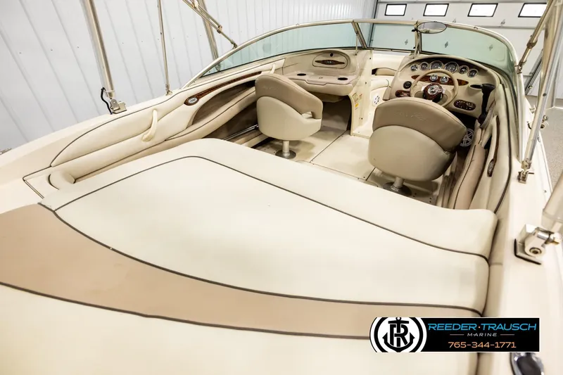 Slide: The Image of 2003 Sea Ray 200 Bow Rider interior with beige seating and dashboard, showcased in a showroom. - 11