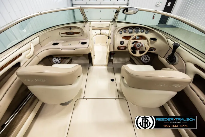 Slide: The Image of Interior of a 2003 Sea Ray 200 Bow Rider boat, featuring beige seating and dashboard. - 13