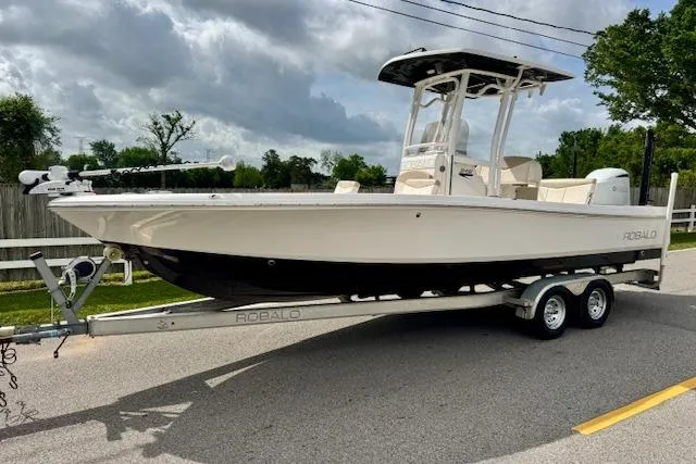 The Image of 2017 Robalo 246 Cayman boat on trailer, parked on road under cloudy sky. - 1