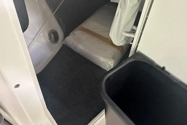 Slide: The Image of Interior storage area of 2025 Yamaha Boats AR220, featuring carpeted flooring and packaged items. - 13