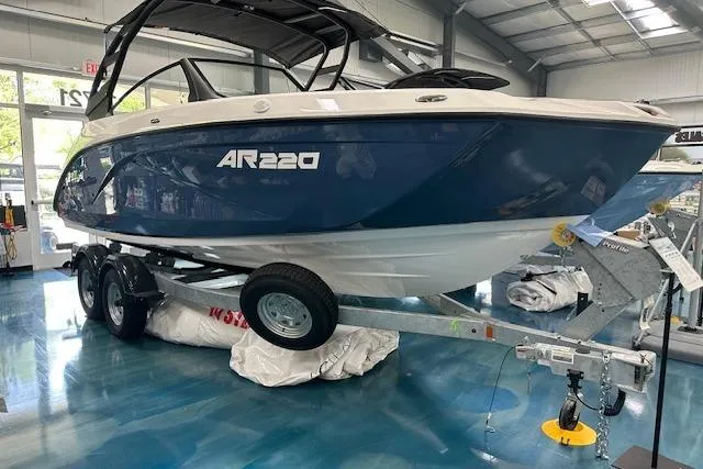 Slide: The Image of 2025 Yamaha Boats AR220 on trailer in showroom, blue and white design. - 3