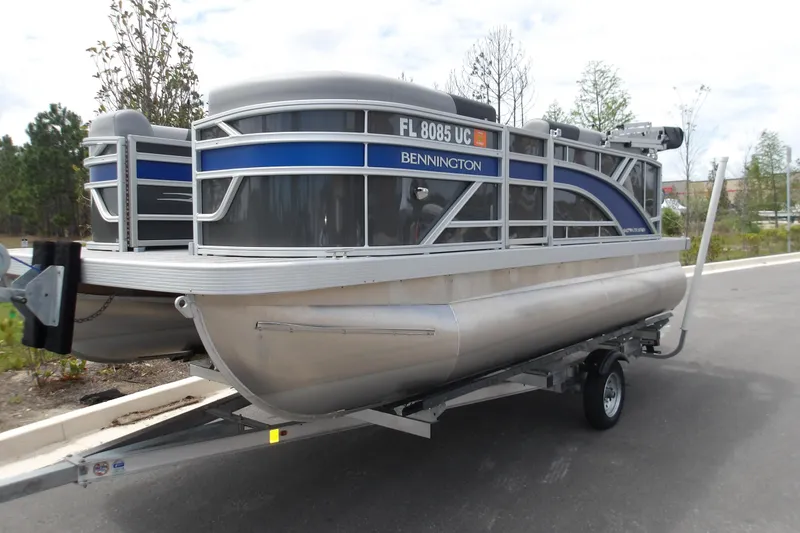 Slide: The Image of 2026 Bennington 16 S L-Bench pontoon boat on trailer, parked outdoors. - 2