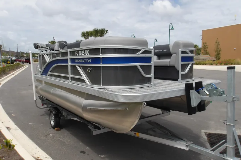 Slide: The Image of 2026 Bennington 16 S L-Bench pontoon boat on trailer, parked outdoors. - 4
