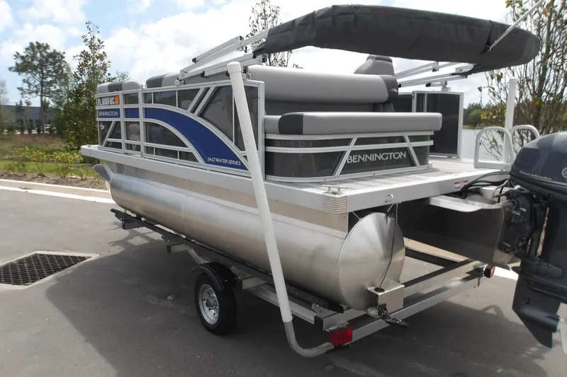 Slide: The Image of 2026 Bennington 16 S L-Bench pontoon boat on trailer, parked outdoors. - 5