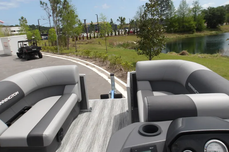 Slide: The Image of 2026 Bennington 16 S L-Bench pontoon boat with gray seating, parked near a pond. - 8