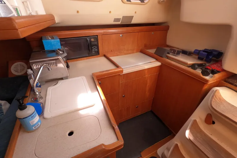 Slide: The Image of 2003 Hunter 326 yacht interior kitchen with wooden cabinetry and appliances. - 10