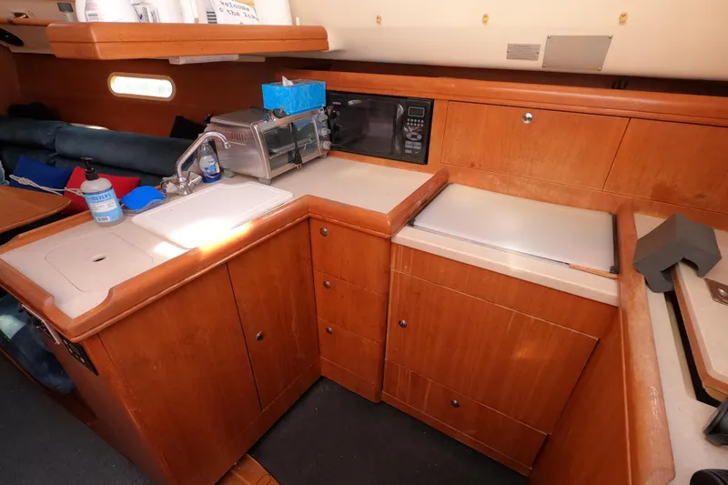 Slide: The Image of 2003 Hunter 326 yacht kitchen with wooden cabinetry, sink, and appliances. - 11