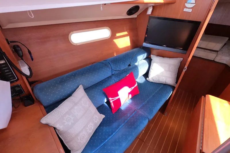 Slide: The Image of Cozy interior of 2003 Hunter 326 sailboat with blue sofa, pillows, and mounted TV. - 16