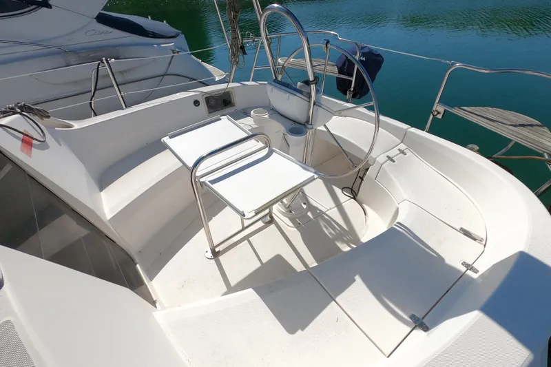 Slide: The Image of 2003 Hunter 326 sailboat cockpit with steering wheel and seating, docked by calm water. - 4