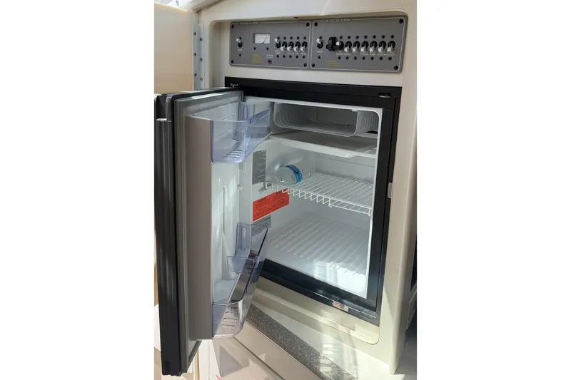 Slide: The Image of Open refrigerator inside a 2001 Formula 330 Sun Sport boat, showing shelves and control panel. - 12
