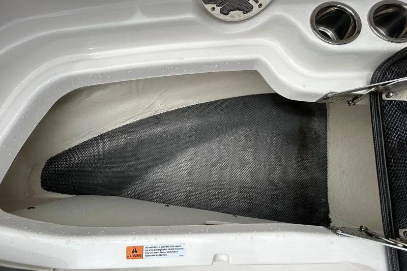 Slide: The Image of Storage compartment in 2020 Chaparral 230 Suncoast boat with cup holders and warning label. - 102