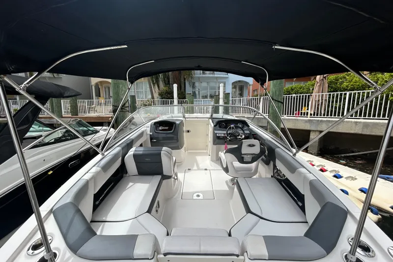 Slide: The Image of 2020 Chaparral 230 Suncoast boat interior with seating and steering wheel under canopy. - 19