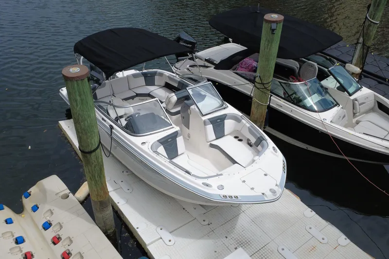 Slide: The Image of 2020 Chaparral 230 Suncoast boat docked, featuring sleek design and spacious seating. - 2