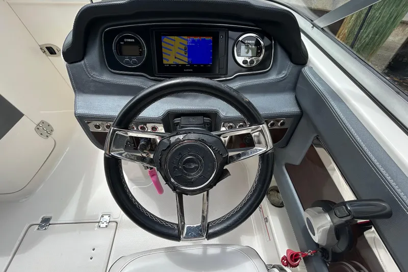 Slide: The Image of 2020 Chaparral 230 Suncoast boat dashboard with steering wheel and navigation display. - 26