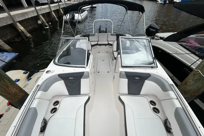 Slide: The Image of 2020 Chaparral 230 Suncoast boat with open deck, docked by the water. - 40