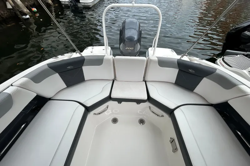 Slide: The Image of 2020 Chaparral 230 Suncoast boat interior with cushioned seating and outboard motor. - 49