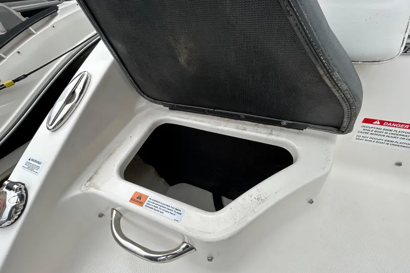 Slide: The Image of Open storage compartment on 2020 Chaparral 230 Suncoast boat with safety warnings visible. - 58
