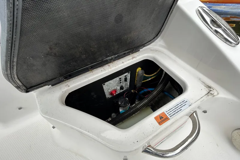 Slide: The Image of Open storage compartment on 2020 Chaparral 230 Suncoast boat, showing wiring and warning label. - 65