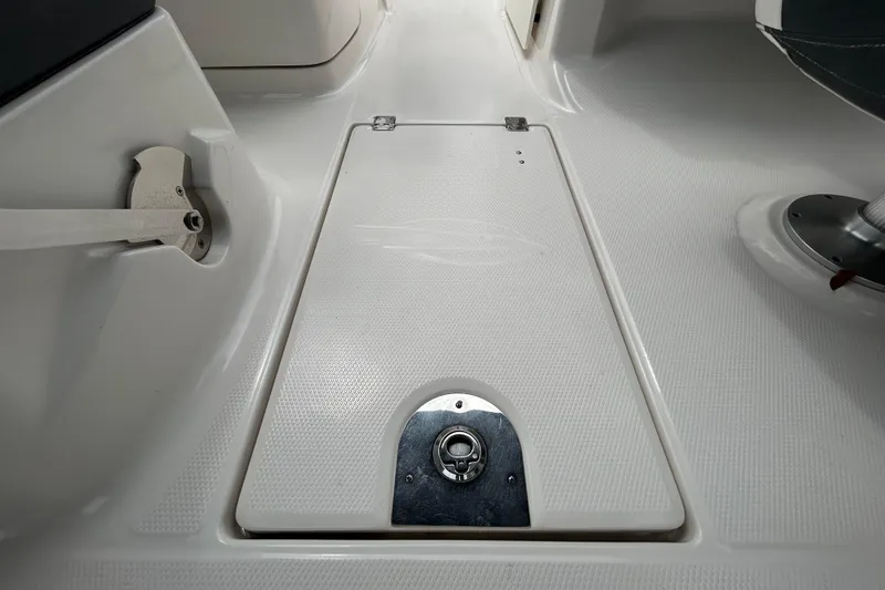 Slide: The Image of 2020 Chaparral 230 Suncoast boat interior, featuring a textured deck and storage compartment. - 82