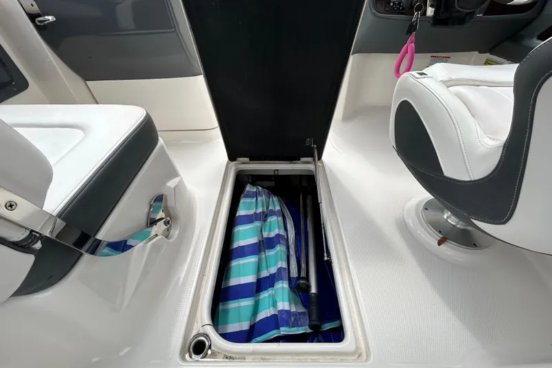 Slide: The Image of 2020 Chaparral 230 Suncoast boat interior with open storage compartment and striped fabric. - 83