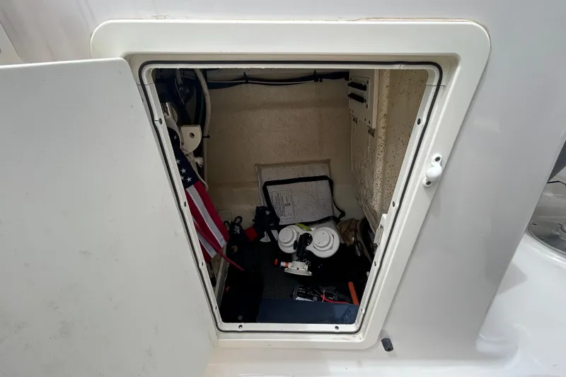 Slide: The Image of Storage compartment of a 2020 Chaparral 230 Suncoast boat, featuring various equipment and an American flag. - 98